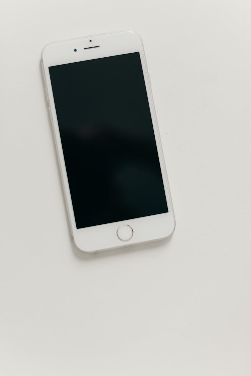 A minimalist flat lay of a smartphone with a blank black screen on a light background.